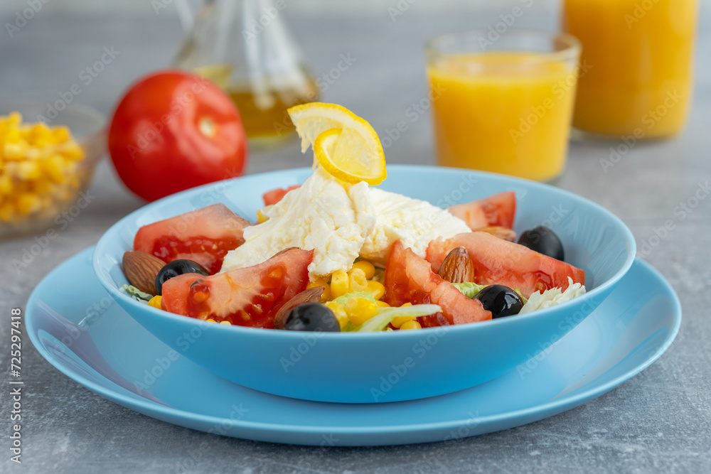 Colorful fresh vegetable salad with mozzarella cheese in bowl and orange juice. Healthy food concept Colorful fresh vegetable salad with mozzarella cheese in bowl and orange juice. Healthy food concept