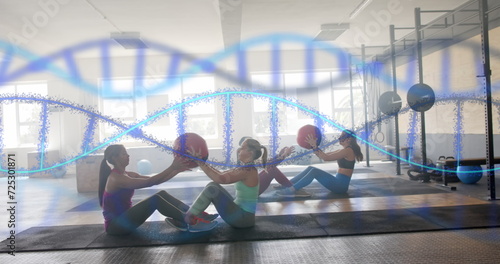 Image of dna strands over diverse women cross training in pairs with medicine balls at gym