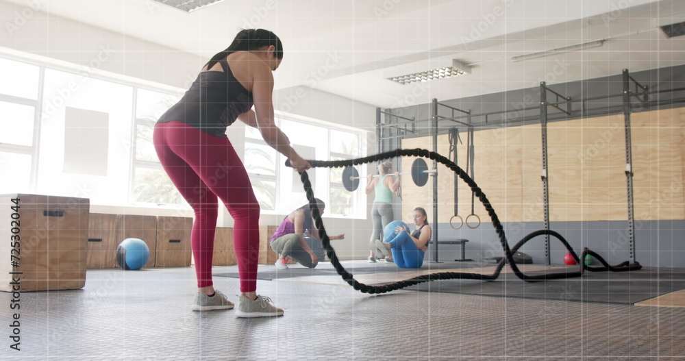Image of graph processing data over caucasian woman cross training with battle ropes at gym