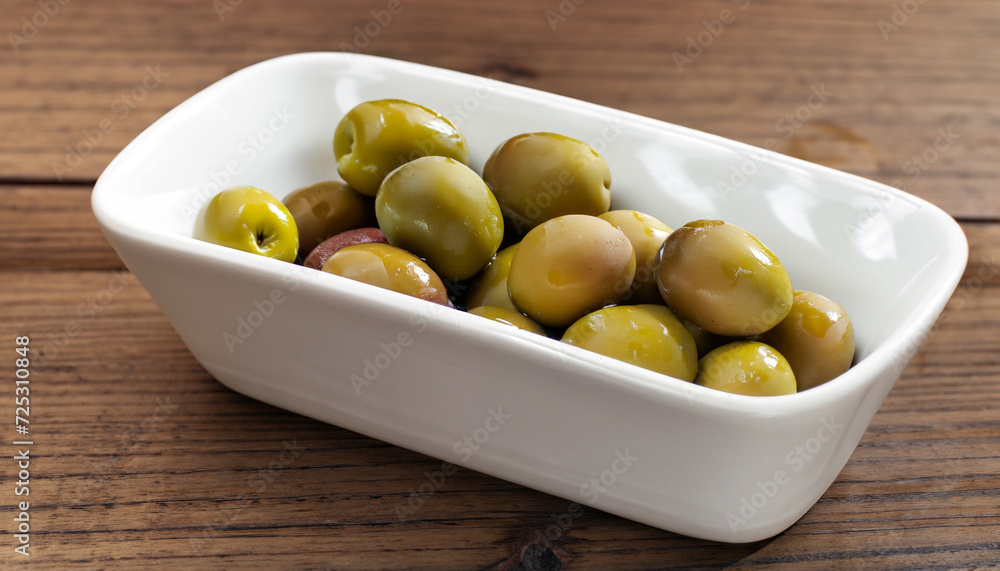 Raw Olives in a white dish on a wooden table Raw Olives in a white dish on a wooden table