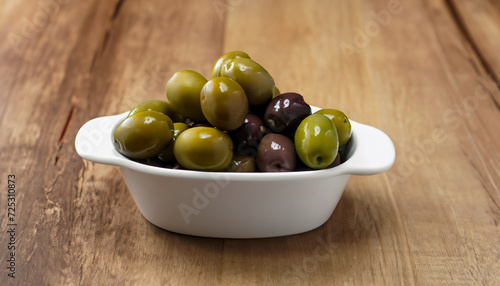 Raw Olives in a white dish on a wooden table