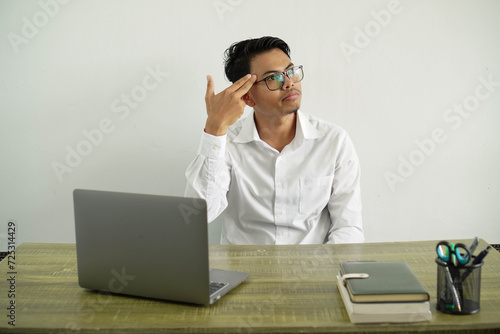 young asian businessman in a workplace with problems making suicide gesture, wearing white shirt with glasses isolated
