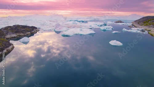 Drone View of Iceberg and ice melting from glacier in arctic nature on Greenland at midnight sun sunset. Sermeq Kujalleq Glacier Affected by Global warming and climate change, Greenland