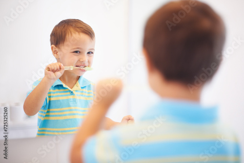 Boy kid  brushing teeth and mirror in bathroom for cleaning  hygiene or health for routine in house. Child  toothbrush or reflection for dental wellness  thinking or results in morning at family home