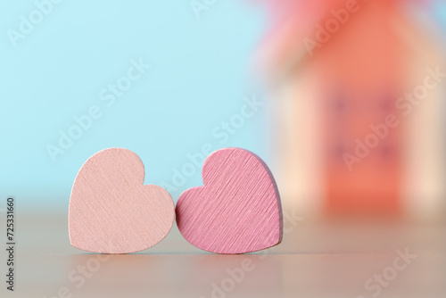 Two decorative hearts over defocused background with house model in red bow. Valentine’s day greeting card