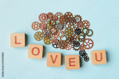 Brain-shaped Gears and Wooden Blocks Spelling ‘Love U’ on Blue Background