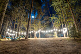 enchanted forest campground with hammocks under starburst lights, a tranquil outdoor retreat nestled among towering trees and night sky