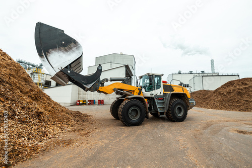 Quadro em tela industrial wheel loader with raised bucket at a biomass power plant, handling wo