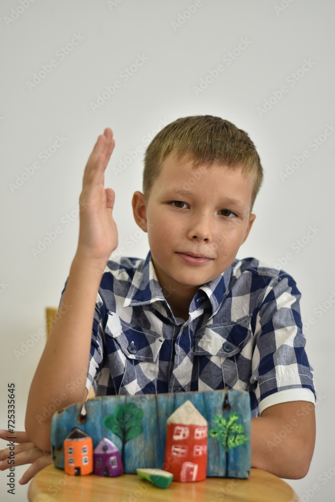 The boy in the plaid shirt raised his hand as if in school before his craft. The boy in the plaid shirt raised his hand as if in school before his craft.