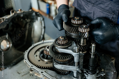 a disassembled gearbox in the hands of an experienced car mechanic who repairs broken mechanisms and parts in a car