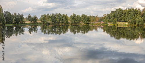 bank with trees along the river, reflection of clouds in the river