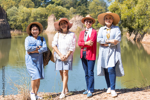 Group of Asian wellness elderly friends reunion hiking in forest together in summer, healthy senior pensioner female in retirement joyful smile looking camera enjoy holiday vacation trip in woods