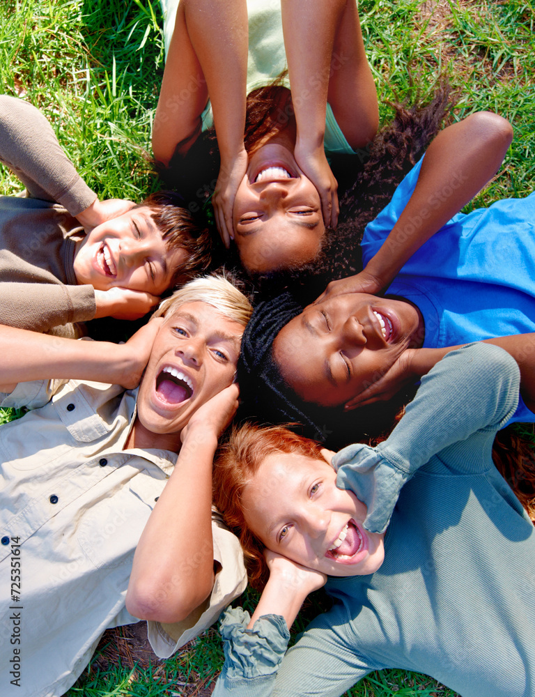 Children, friends and cover ears in outdoors for silence, quiet and ignoring noise in nature. Diversity, kids and laughing for humor or funny joke on grass, top view and bonding in childhood for fun