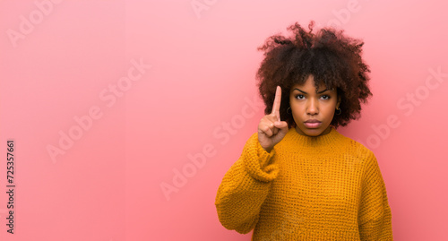Portrait of african american woman isolated on pink background. dark skinned woman shows finger at upper corner isolated over pink background. Banner. Copy space.