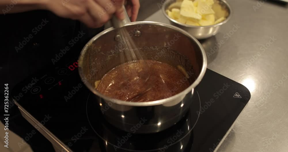 Adding and mixing butter to chocolate mousse to make a dessert. Chocolate preparation, professional kitchen, baking, confectionery Adding and mixing butter to chocolate mousse to make a dessert. Chocolate preparation, professional kitchen, baking, confectionery