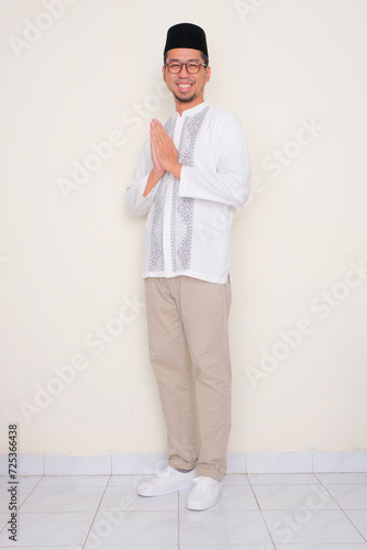 Full body portrait of Moslem man smiling friendly do greeting pose photo