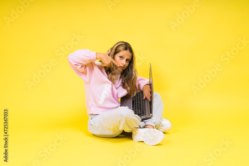 Teenager girl with notebok computer laptop sitting in studio photo