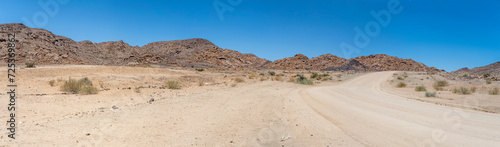 gravel road and Dolerite boulder buttes in desert, near Hobas,  Namibia