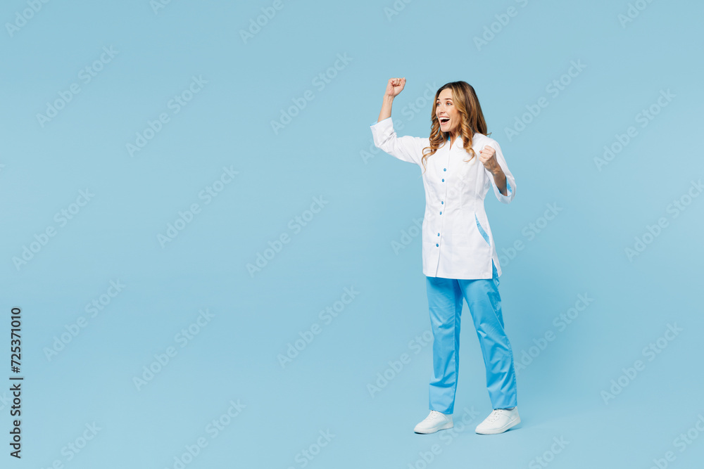 Full body side view female doctor woman wear white medical gown suit work in hospital clinic office do winner gesture look aside isolated on plain blue background studio. Health care medicine concept Full body side view female doctor woman wear white medical gown suit work in hospital clinic office do winner gesture look aside isolated on plain blue background studio. Health care medicine concept