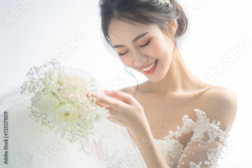 お花を持つウェディングドレス姿の笑顔の日本人女性（前撮り・結婚式・ウェディングフォト） photo