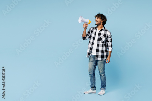 Full body young Indian man he wears shirt white t-shirt casual clothes hold in hand megaphone scream announces discounts sale Hurry up isolated on plain pastel blue cyan background. Lifestyle concept. © ViDi Studio