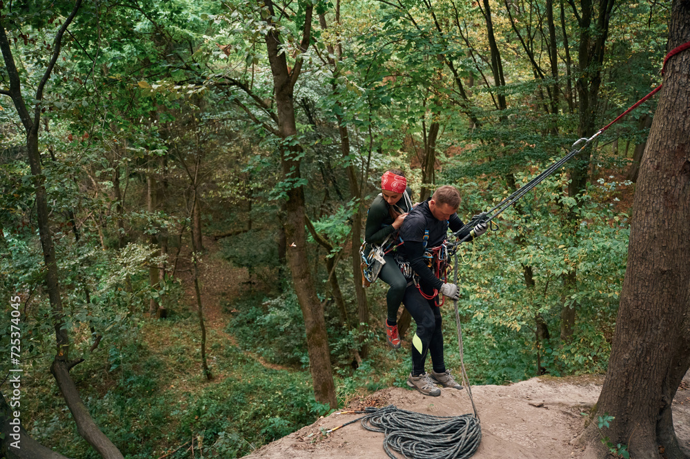 Obraz premium In the forest. Man and woman doing climbing with use of safety equipment