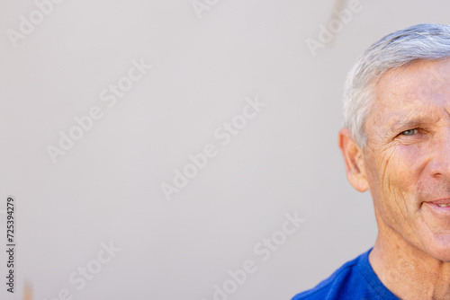 Half portrait of smiling caucasian senior man in front of grey wall with copy space photo