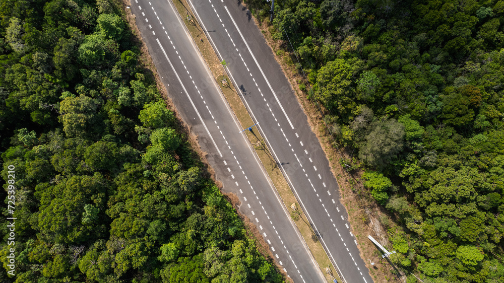 Aerial view of a multilane highway cutting through lush green forestry, embodying concepts of transportation, infrastructure, and the environment