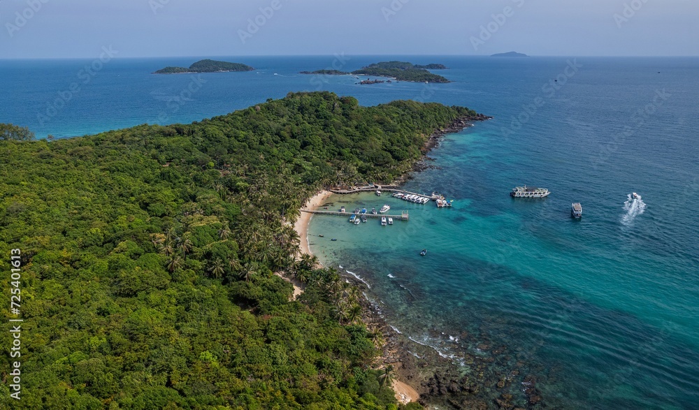 Aerial view of a tropical island with lush greenery, a sandy beach, and boats on clear blue waters, ideal for vacation and travel concepts,  Earth Day concept