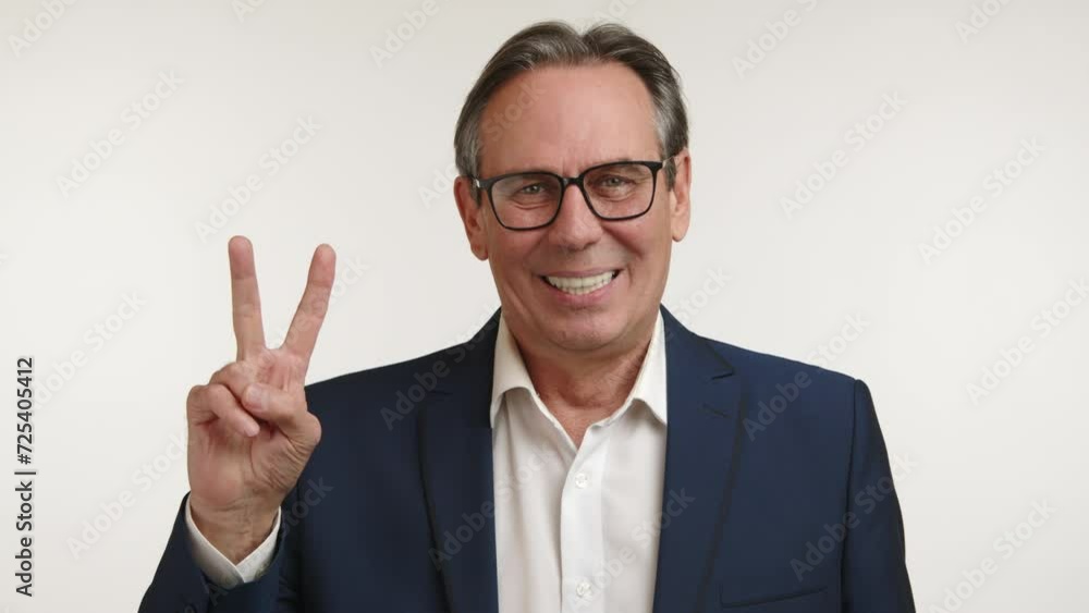 Relaxed and friendly businessman in a blue suit making a peace sign, conveying a message of positivity and approachability. High quality 4k footage