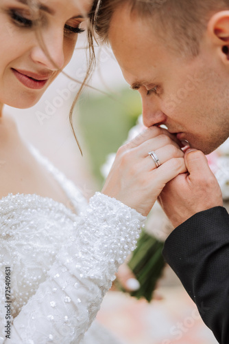 Wedding kiss. Groom kisses bride's hand. Weddng love. Close-up of a young man kissing his wife's hand with gold ring while making a marriage proposal. photo