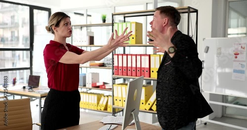 Angry man yelling at angry businesswoman and loud quarrel at workplace. Angry colleagues partners in rage point fingers and yell at each other photo