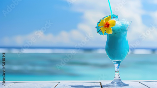 Blue hawaii cocktail on white wooden table with blue sea and sky background.