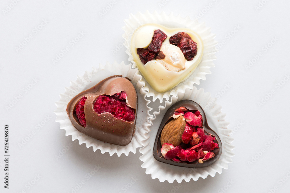 chocolate sweets in the form of a heart with fruits and nuts on a colored background. top view with space for text, holiday concept chocolate sweets in the form of a heart with fruits and nuts on a colored background. top view with space for text, holiday concept