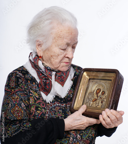 Portrait of old woman with icon posing in studio