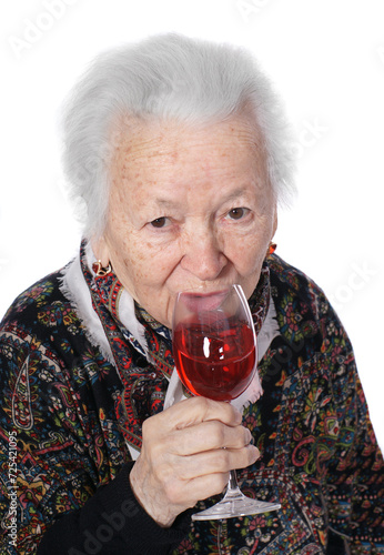 Old woman with glass of red wine posing in studio