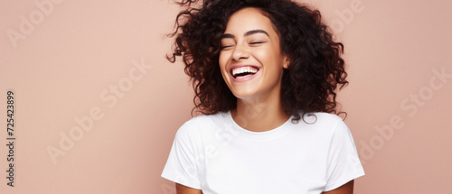 Young happy smiling Latin woman model wearing tshirt standing on color background. Face skin treatment, curly hair care cosmetics makeup, fashion ads. Beauty portrait. White t-shirt mock up template .