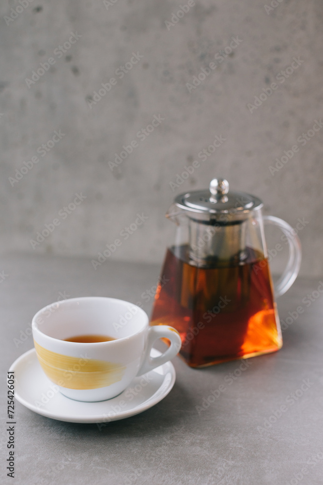 Glass teapot and cup with aromatic tea isolated on gray background. Glass teapot and cup with aromatic tea isolated on gray background.
