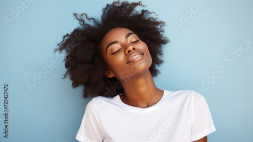 Young adult pretty African American woman model wearing white t-shirt with eyes closed on background. Face flawless fresh skin hair care cosmetic treatment makeup products skincare ad. Beauty portrait