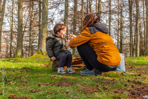 Mother feeding her son sitting in a tree in a forest on Mount Erlaitz in Irun  Basque Country