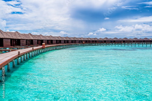 Scenic view of water villas in Maldives with turquoise pristine water and dramatic storm sky  © Horia Merla