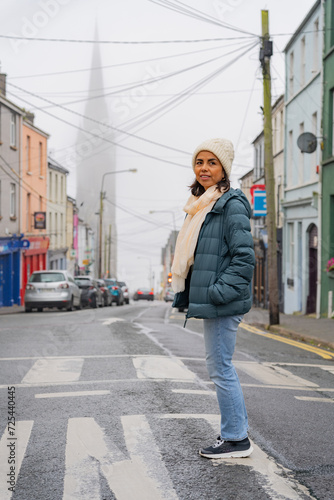 Beautiful latin woman with a Knit hat enjoying a walk through a picturesque town in Ireland on her road trip through the country