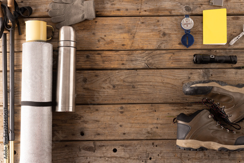 Outdoor hiking gear is neatly arranged on a wooden surface, with copy space © vectorfusionart