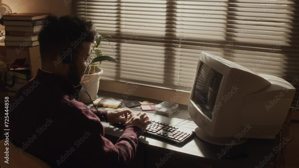 Back view of Biracial male programmer putting on wired headphones and ...