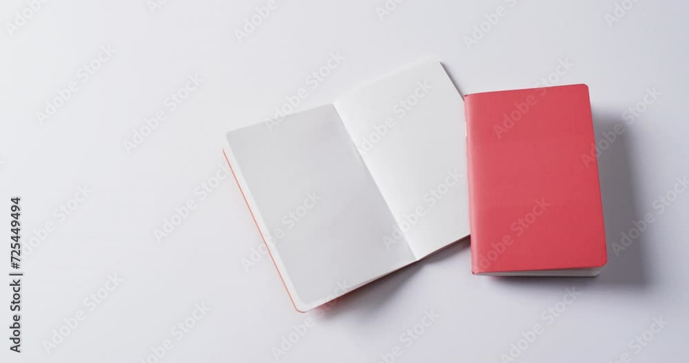 Close up of closed red book and open blank book with copy space on white background in slow motion Close up of closed red book and open blank book with copy space on white background in slow motion
