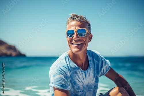 Portrait of happy senior man in sunglasses sitting on the beach and laughing © Nerea