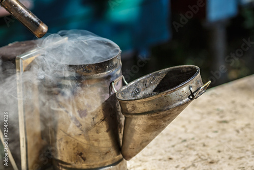 Old bee smoker.A tool of the beekeeper.Wooden beehive and bees. Beekeeper Inspecting Bee Hive