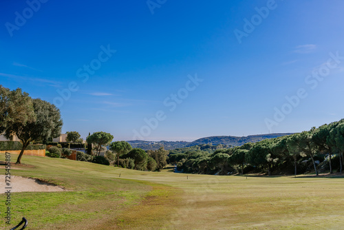 Sotogrante, Spain - January 25, 2024 - The photo captures a sunny golf course with clear skies, a variety of trees, and distant hills.