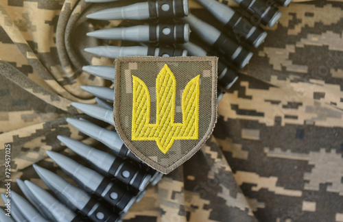 Ukrainian army symbol on machine gun belt lies on ukrainian pixeled military camouflage close up photo