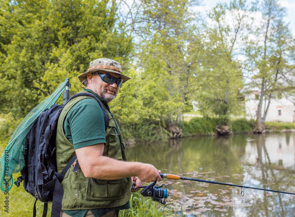 Senior fisherman holding a fishing rod with a spinning reel, getting ready to catch a fish. Fishing equipment and skills concepts. Senior fisherman holding a fishing rod with a spinning reel, getting ready to catch a fish. Fishing equipment and skills concepts.